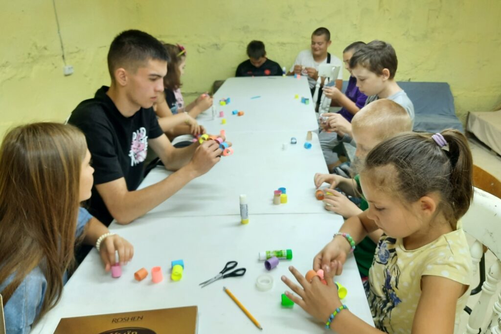 Діти майструють за столом поробки з паперу